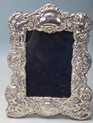 A silver and oak easel backed picture frame decorated with cherubs, puttis, a medieval greenman,