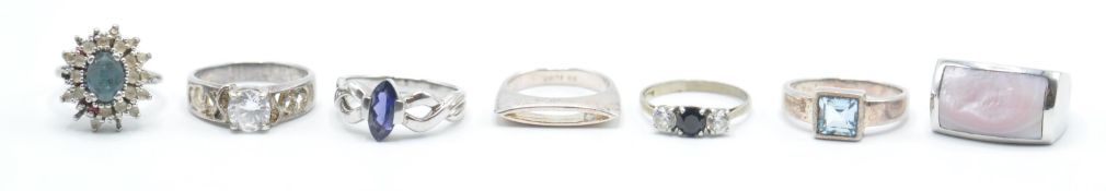 A group of seven silver ladies rings to include a pink stone panel ring, a three stone ring set with