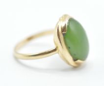 A stamped 14ct gold ring being set with a oval green stone cabochon set within a gold mount.