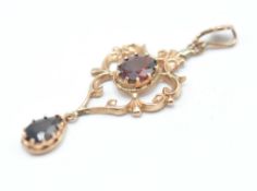 A 20th Century 9ct gold Renaissance style pendant being set with an oval cut red stone and