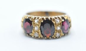A hallmarked 9ct gold ring being set with three oval cut red stones with six round cut white