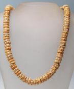 An 20th century bone carved beaded necklace having circular beads with incised decoration to each