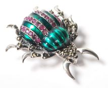 A stamped .925 silver ladies brooch in the form of an insect with green decoration to its body.