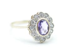 A hallmarked 9ct gold ladies cluster ring having a central oval cut purple stone with a halo of