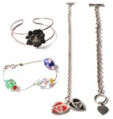 A group of silver ladies bracelets to include a split band band with a black enamelled flower (