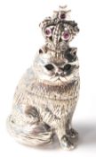 A sterling silver figurine of a cat wearing a crown having eyes and crown inset with stones.