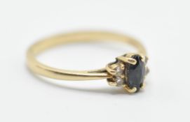 A 14ct gold ring set having a blue oval central stone flanked by four white stone with pierced
