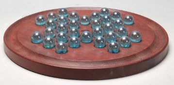 An early 20th Century Edwardian mahogany solitaire board of round form having 32 green glass marbles