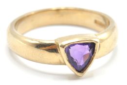 A hallmarked 9ct gold old band ring being bezel set with a triangular cut purple stone. Hallmarked