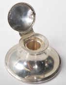 A silver hallmarked ink well of round form having a domed hinge lid to the top opening to reveal a