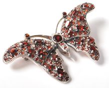 An Art Nouveau style stamped sterling silver and garnet pinback brooch in the form of a butterfly.