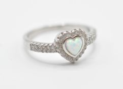 A stamped .925 silver ladies dress ring having a heart shaped opal set within a halo of accent