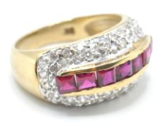 A stamped 9ct gold ring being set with a row of square cut red stones surrounded by two rows of
