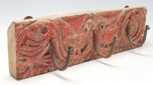 A 20th Century carved folk art wooden wall mounting set of coat hooks decorated with peacocks with