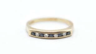 A hallmarked 9ct gold ring being channel set with alternate blue and white stones. Hallmarked