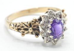 A hallmarked 9ct gold ladies dress ring being set with an oval cut purple stone with a halo of white