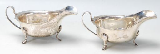 A pair of silver 20th century gravy boat having a wavy rim, three hoof supports and flat band shaped