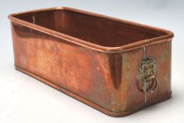 A vintage copper planter trough of rectangular form having a lipped edge and a lions head handle