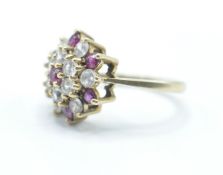A hallmarked 9ct gold cluster ring being set with round cut red and white stones. Hallmarked