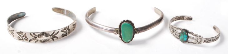 Two stamped sterling silver Native American bangle bracelets each being set with turquoise stones,