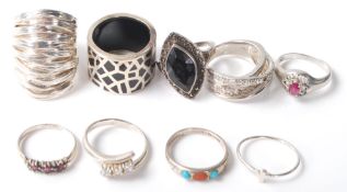 A collection of nine silver rings to include a crossover ring set with three round cut white stones,