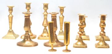 A good collection of mid 20th Century brass candlesticks raised on squared, circular and oval