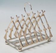 An unusual silver plated toast rack having a hoop carry handle over crossed rifle shaped