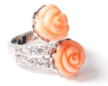 A stamped .925 silver crossover ladies dress ring having a twin flower shaped coral stone with CZ