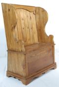 A contemporary antique style vintage two seat country pine pine monks bench with shaped arm rests