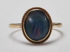 A hallmarked 9ct gold ring set with an oval opalescent cabochon with rope twist to the mount.