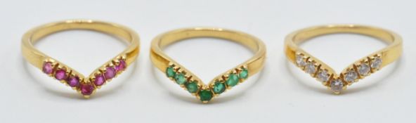 A set of three 18ct yellow gold wishbone style rings set with white diamond, rubies and emeralds