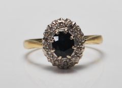 A hallmarked 18ct gold ring being set with an oval cut blue stone having white accent stones to