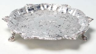A George II silver hallmarked salver of circular form with scalloped edge being raised on hoof feet.