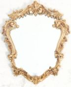 An antique style Rococo wall mirror of scrolled form. The central mirror panel held within a faux