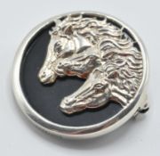 A sterling silver and onyx brooch set with three horse heads. Measures: 3cm diameter. weight 12.8g