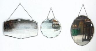 A group of three mid Century frameless mirrors to include a round bevelled edge mirror, an oval