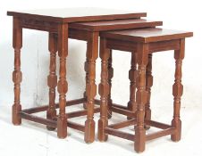 A set of antique style teak wood nest of graduating tables having a flared top over turned block
