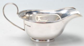 A silver English hallmarked gravy boat having flat ban curved handle and flat plinth base with