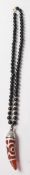 A contemporary Chinese beaded necklace having a black bead necklace with a red stone tooth shaped