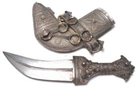 An early 20th Century Islamic white metal curved dagger / jambiya having a short curved blade with a