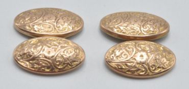 A pair of 1930's 9ct gold cufflinks of oval form being engraved with foliate decoration united by