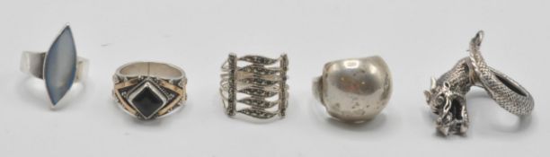 A group of five silver rings to include a stamped 925 silver Chinese dragon ring in the form of a