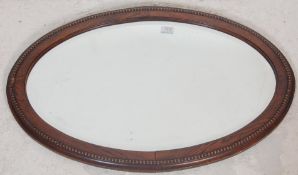 A good early 20th century antique wall hanging mirror in oval shaped with bevelled glass and oak