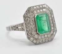 A platinum emerald and diamond cocktail ring. The ring set with a central octagon cut emerald having