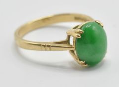A hallmarked 18ct gold ring being prong set with a oval green jade cabochon and engraved