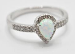 A stamped 925 silver ring having a central opal stone in a shape of teardrop and CZ accent stones.
