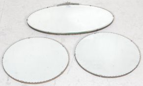 A group of three early 20th century Art Deco wall hanging mirrors. An oval beveled glass mirror with