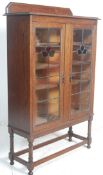 A 1920's oak stained and leaded glass bookcase display cabinet. Raised on block and turned legs