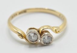 A vintage 20th Century 18ct gold and diamond crossover ring being set with two round cut diamonds in