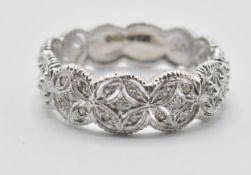 A 9ct white gold eternity ring having a repeating pierced decoration set with diamond accent stones.